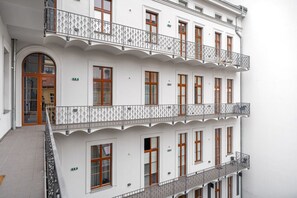 Un immeuble à plusieurs étages, doté de façades blanches, de fenêtres à cadre en bois et de balcons décoratifs.