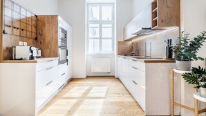 Eine moderne Küche mit weißen Schränken, Holzdetails und einem zentralen Fenster.