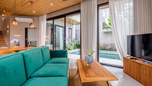 Ein modernes Wohnzimmer mit einem grünen Sofa, einem Holztisch und einem Fernseher auf einer Holzkommode.
