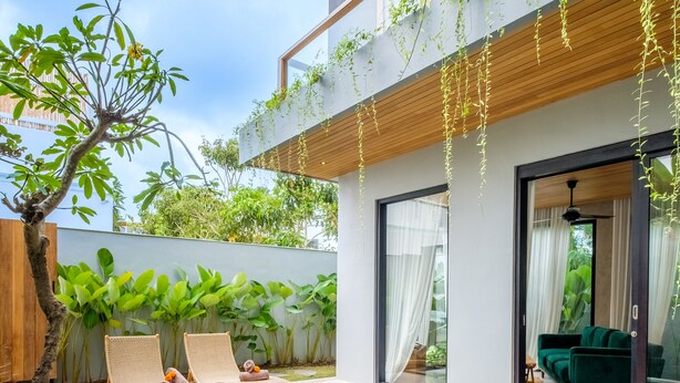 Ein modernes Haus mit Schwimmbad, zwei Liegestühlen und einem grünen Sofa.