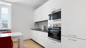 Et moderne køkken med hvide skabe, en ovn i rustfrit stål og et vindue med udsigt.
