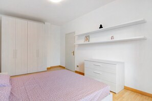 Une chambre à coucher comprenant un lit, une armoire, une commode et une étagère avec un cadre photo et un petit récipient.