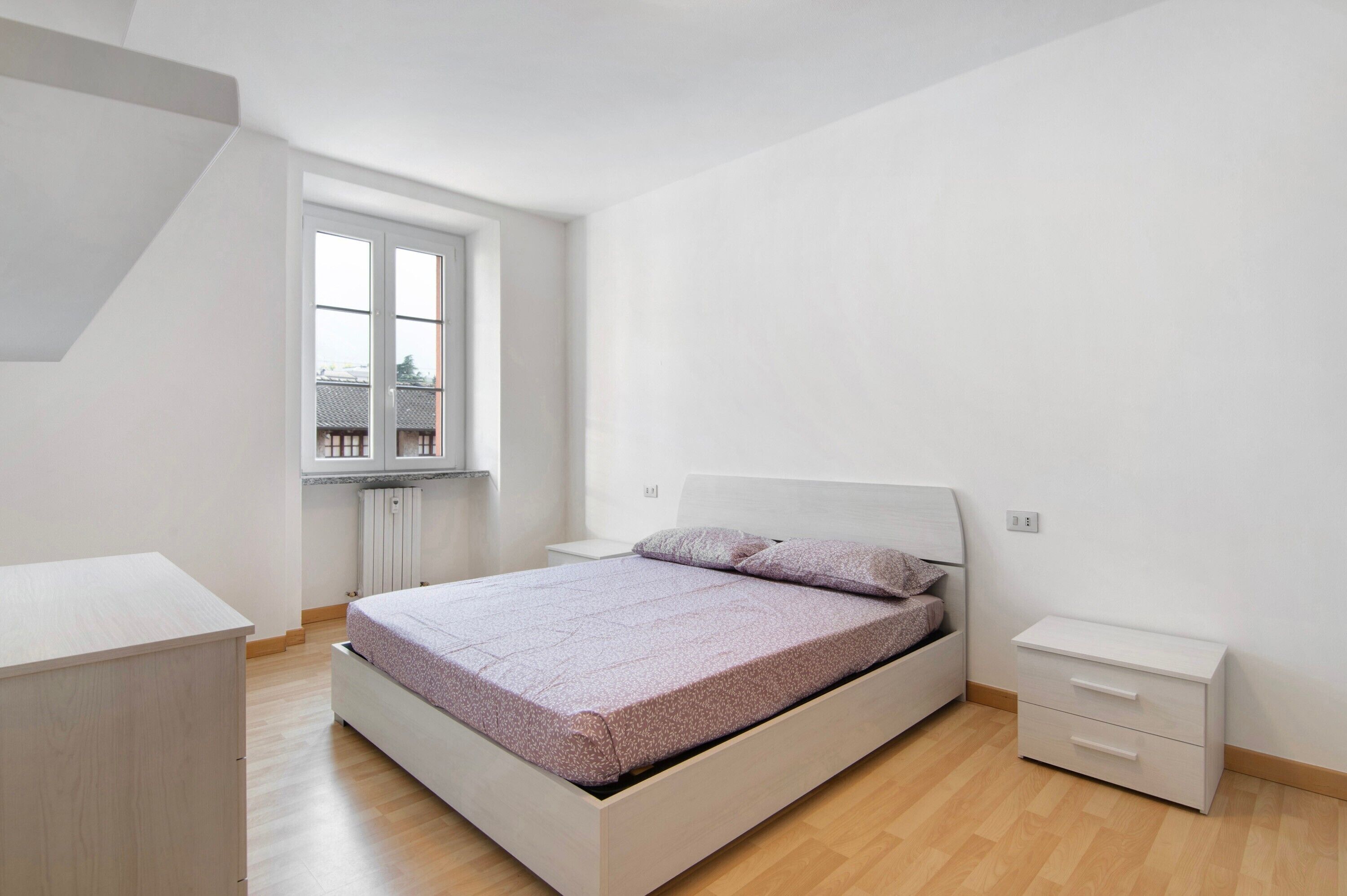 Un dormitorio con cama, mesita de noche, cómoda y ventana.