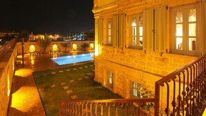 Ein historisches Gebäude mit Schwimmbad, aufwendiger Eisengeländer und einem gut beleuchteten Innenhof bei Nacht.