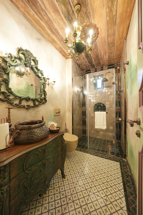 Un baño con diseño vintage, que presenta techo de madera, espejo ornamentado y lavamanos antiguo.