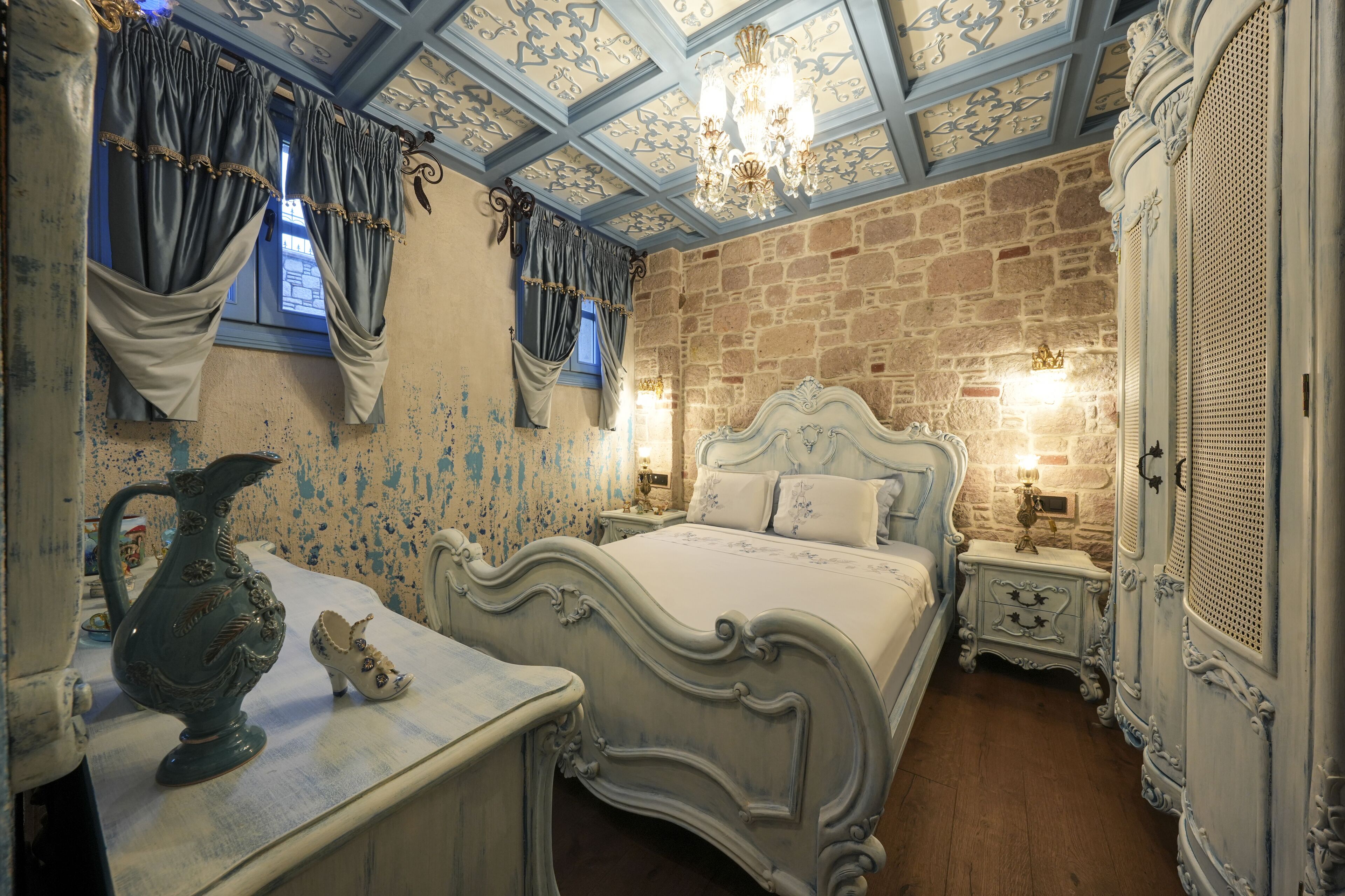 A room with a bed, nightstands, a dresser, and a chandelier.
