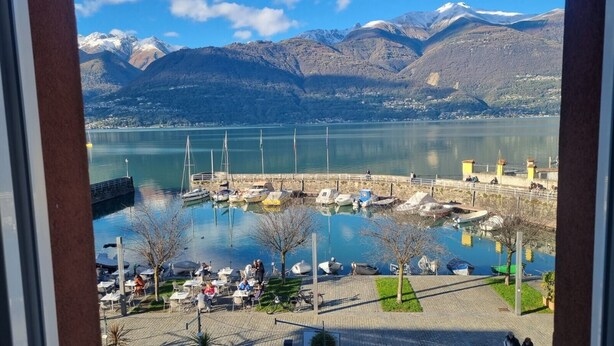 Una marina con imbarcazioni ormeggiate, un molo e vista sulle montagne sullo sfondo.