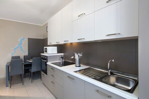 A modern kitchen with a microwave, sink, and dining area. - Holiday Apartment "Colico Center" with Lake View and Wi-Fi (Colico)