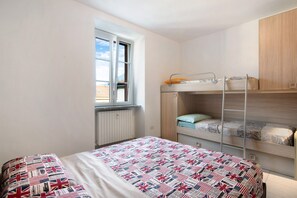 Ein Schlafzimmer mit Etagenbett, einem Fenster mit Blick, einem Heizkörper und einer gesteppten Bettdecke.