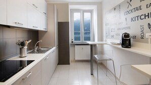 Una cucina moderna con pensili bianchi, un piano cottura nero, una finestra con vista e una parete decorata con parole a tema alimentare.