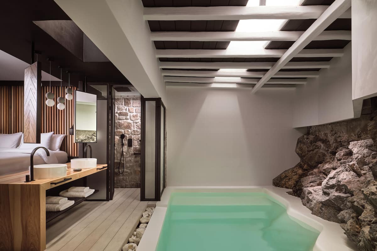 A spa room with a wooden floor, a bathtub, and a stone wall.