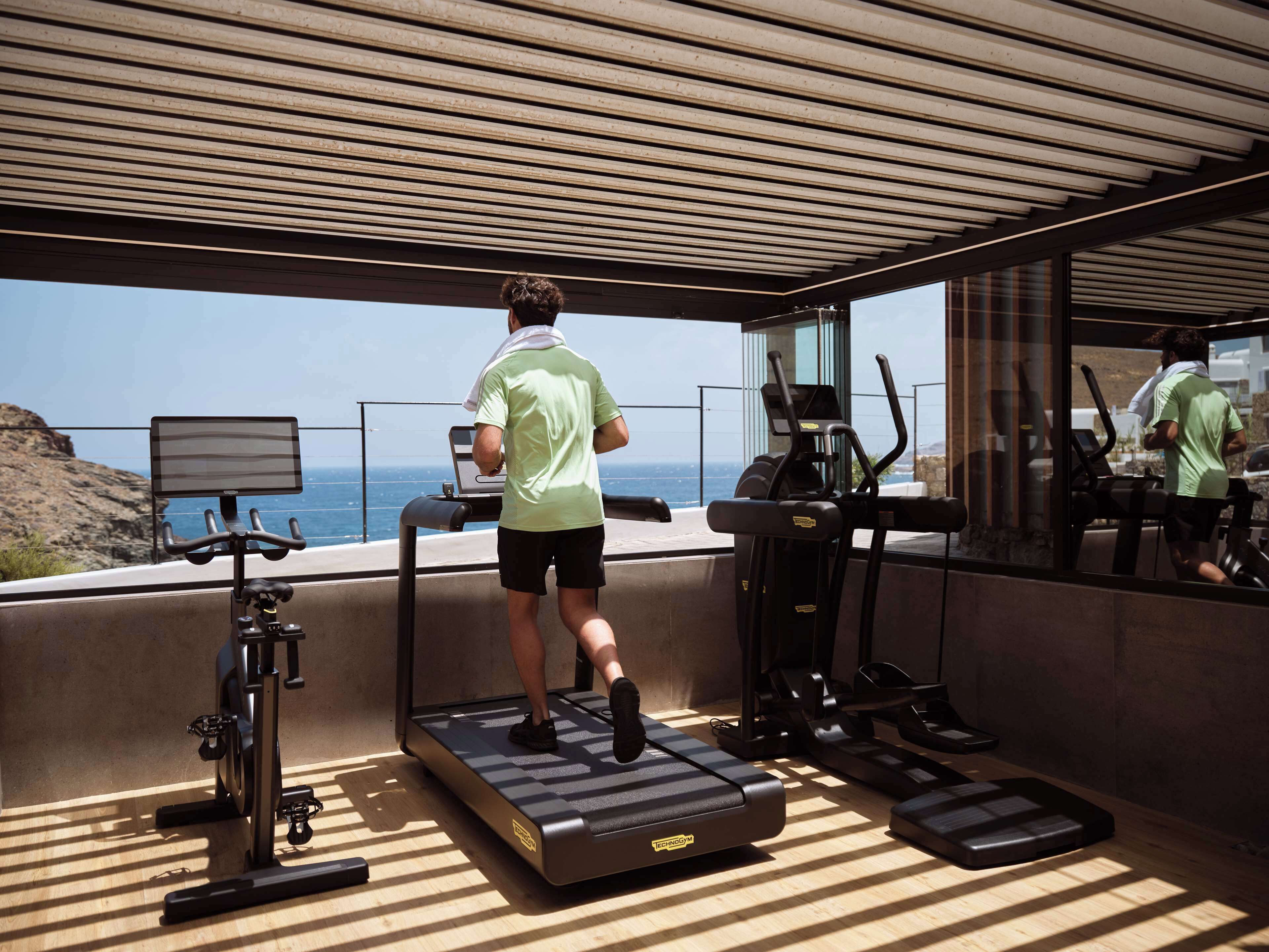 Une salle de sport moderne, dotée de tapis de course et d’appareils d’exercice, offrant une vue panoramique.