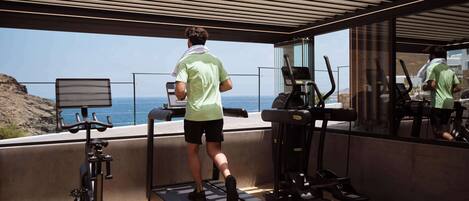 Une salle de sport moderne, dotée de tapis de course et d’appareils d’exercice, offrant une vue panoramique.