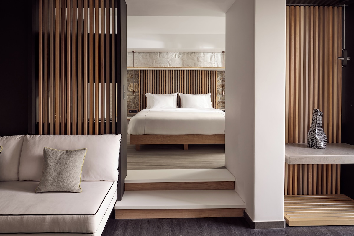 Una habitación de hotel moderna con una cama, un sofá y una pared de listones de madera.