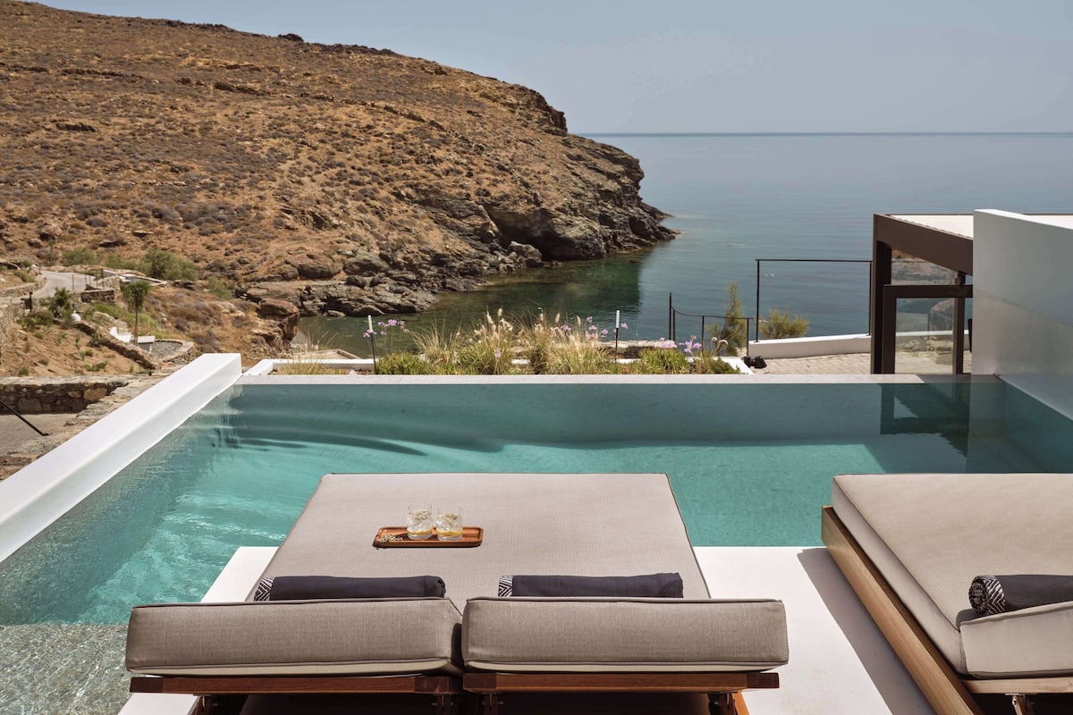 A poolside area with lounge chairs and a view of the sea.