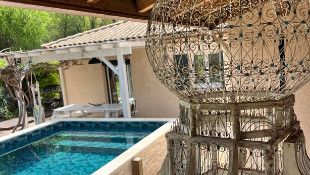 A wooden deck with a swimming pool, a decorative metal lantern, and a pergola structure. - Holiday Home with Spa and Pool (montrem)