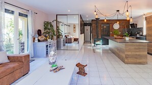 A spacious living area with a sofa, a coffee table, and a dining area with a kitchen in the background. - Holiday Home with Spa and Pool (montrem)