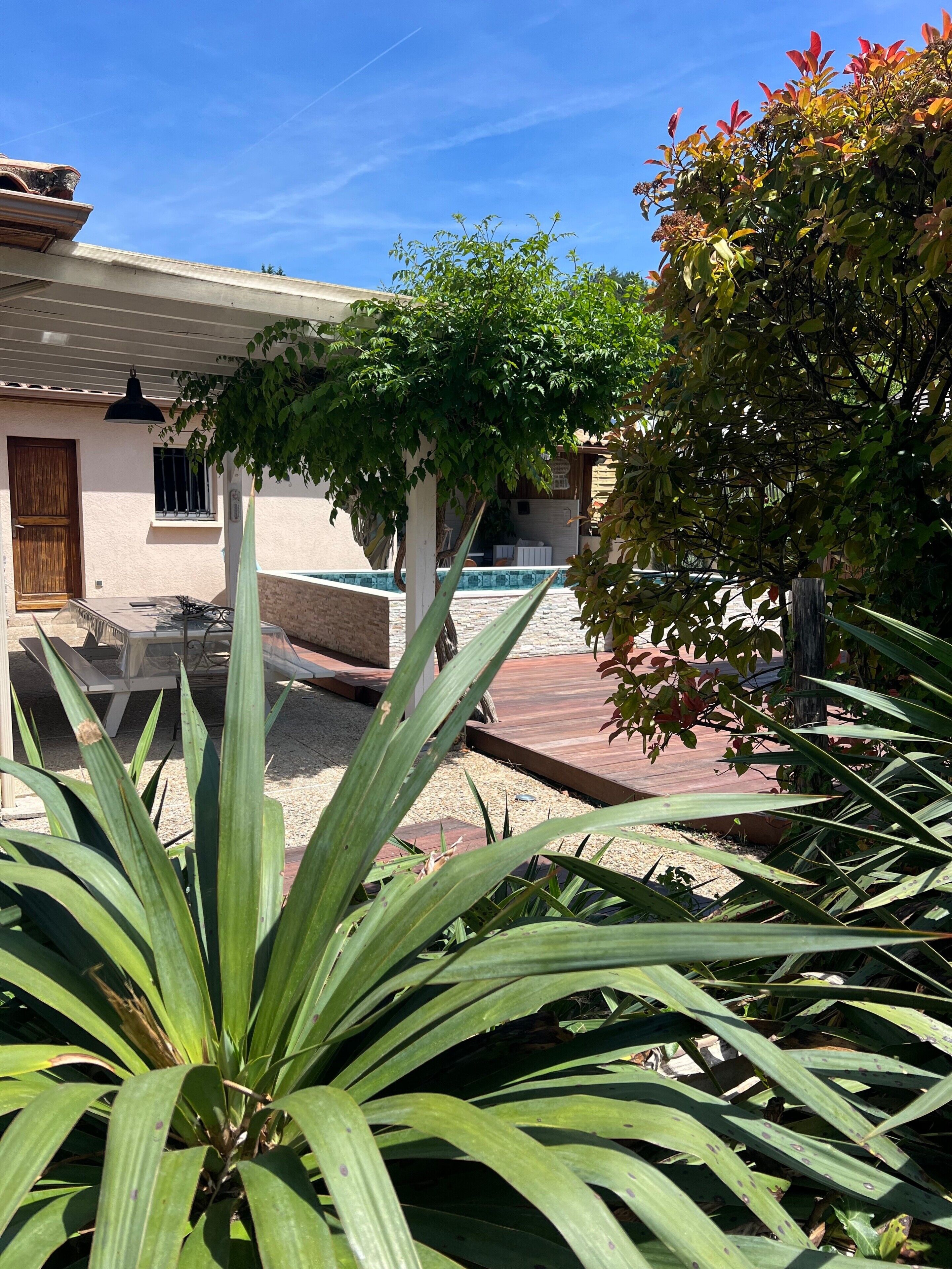 Un patio con piscina, una pérgola y una terraza de madera.