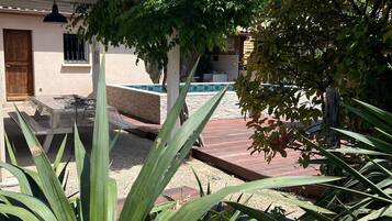 Un patio con piscina, una pérgola y una terraza de madera.