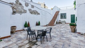 Un patio con una mesa redonda y sillas, una escalera y una puerta verde.