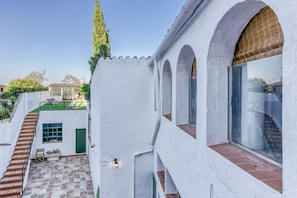 Un bâtiment blanc doté d’un patio carrelé, d’un escalier et offrant une vue sur la maison voisine.