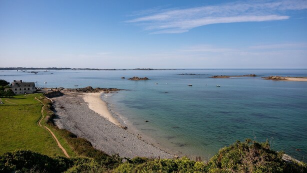 A coastal landscape with a sandy beach, clear blue water, and distant rocky outcrops. - Maison de pecheur en pierres  bord de mer 300 m (Pleubian)