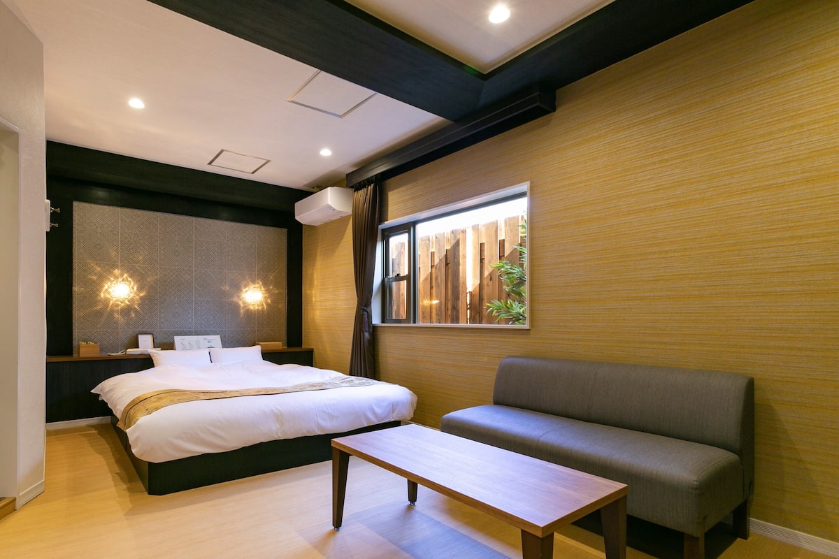 Een moderne hotelkamer met een bed, een bank en een bijzettafeltje.