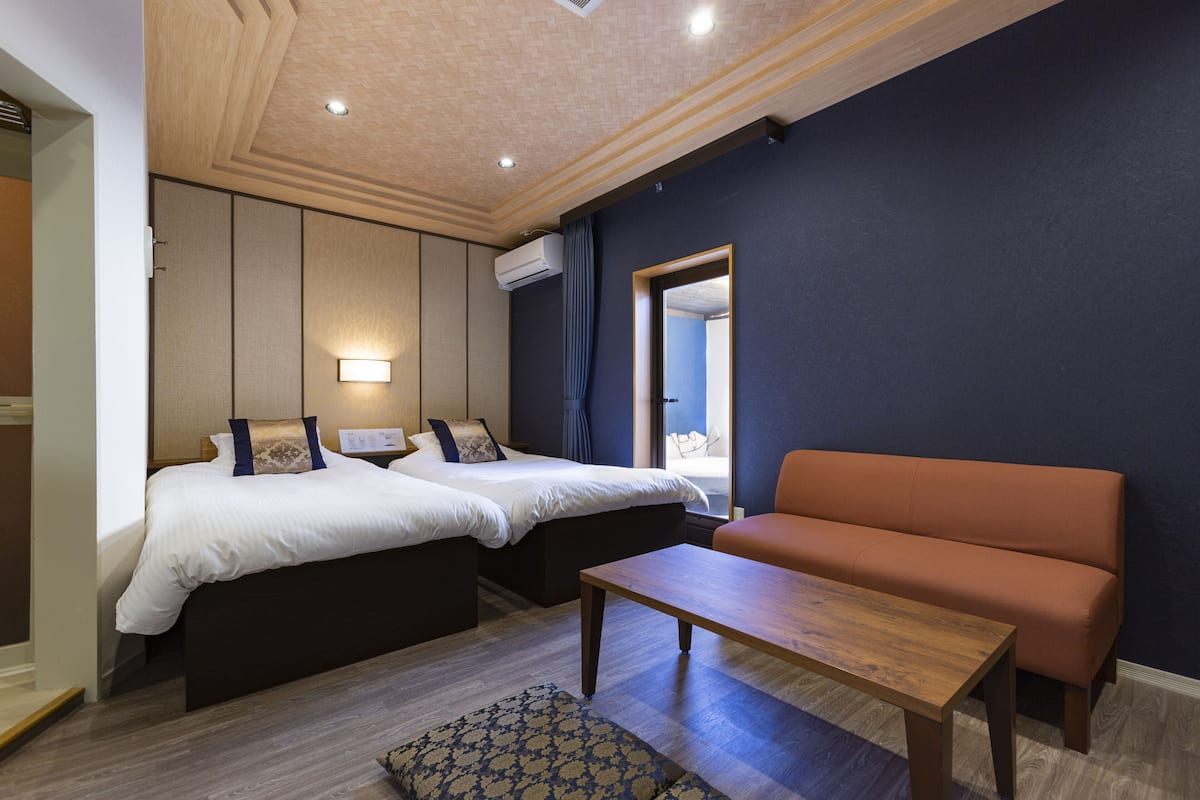 Een hotelkamer met twee bedden, een bank, een houten tafel en een kamerkleed met dessin.