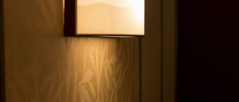 A wall-mounted lamp with a rectangular shade and a patterned wall behind it.
