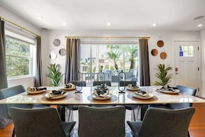 Un espace repas avec une longue table, des chaises et une vue sur l’extérieur.