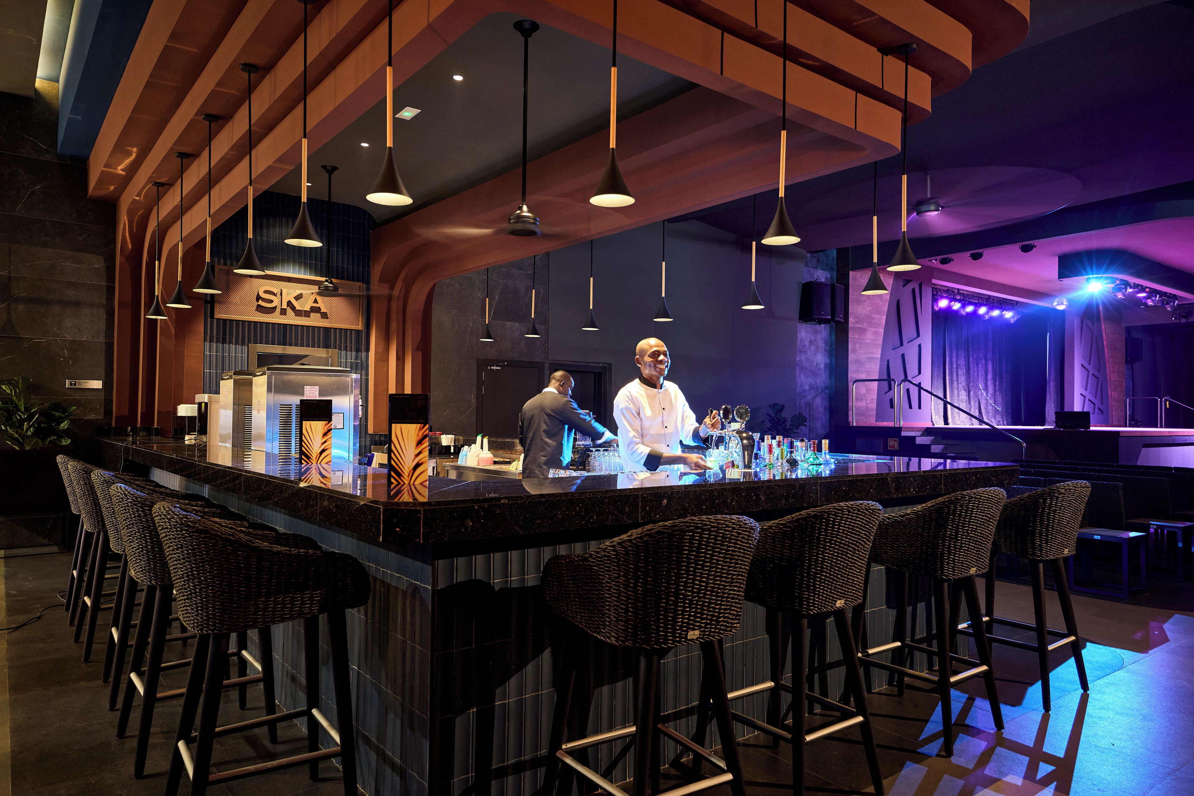 Un'area bar con un bancone, sgabelli e lampade a sospensione.