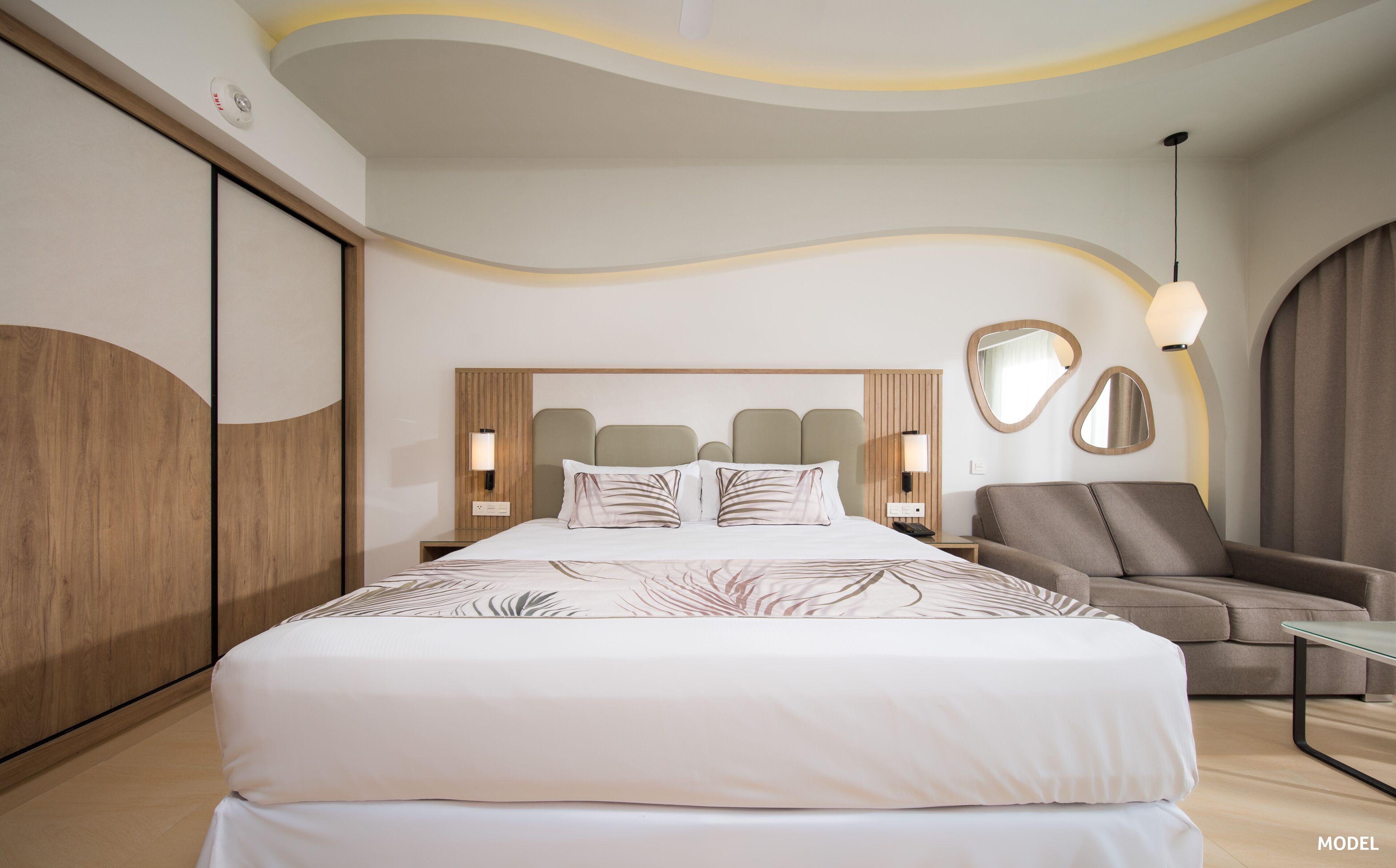 A modern hotel room with a large bed, a sofa, and a desk.