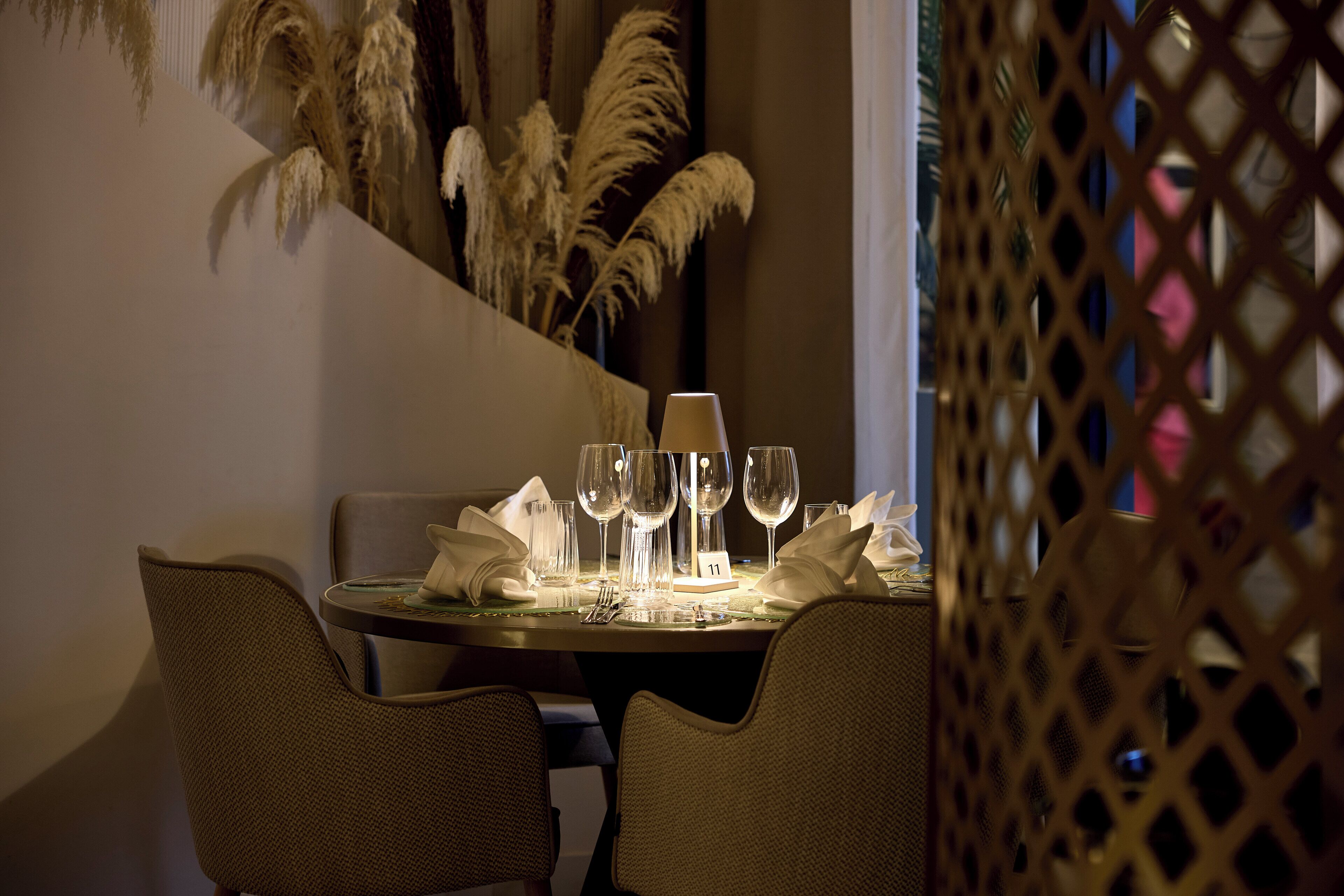 A dining table set with wine glasses, a candle, and a number card.