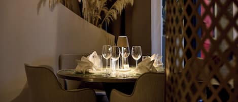 A dining table set with wine glasses, a candle, and a number card.