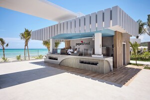 Un ristorante moderno all'aperto con vista sull'oceano, con un bancone con un logo e due membri dello staff.