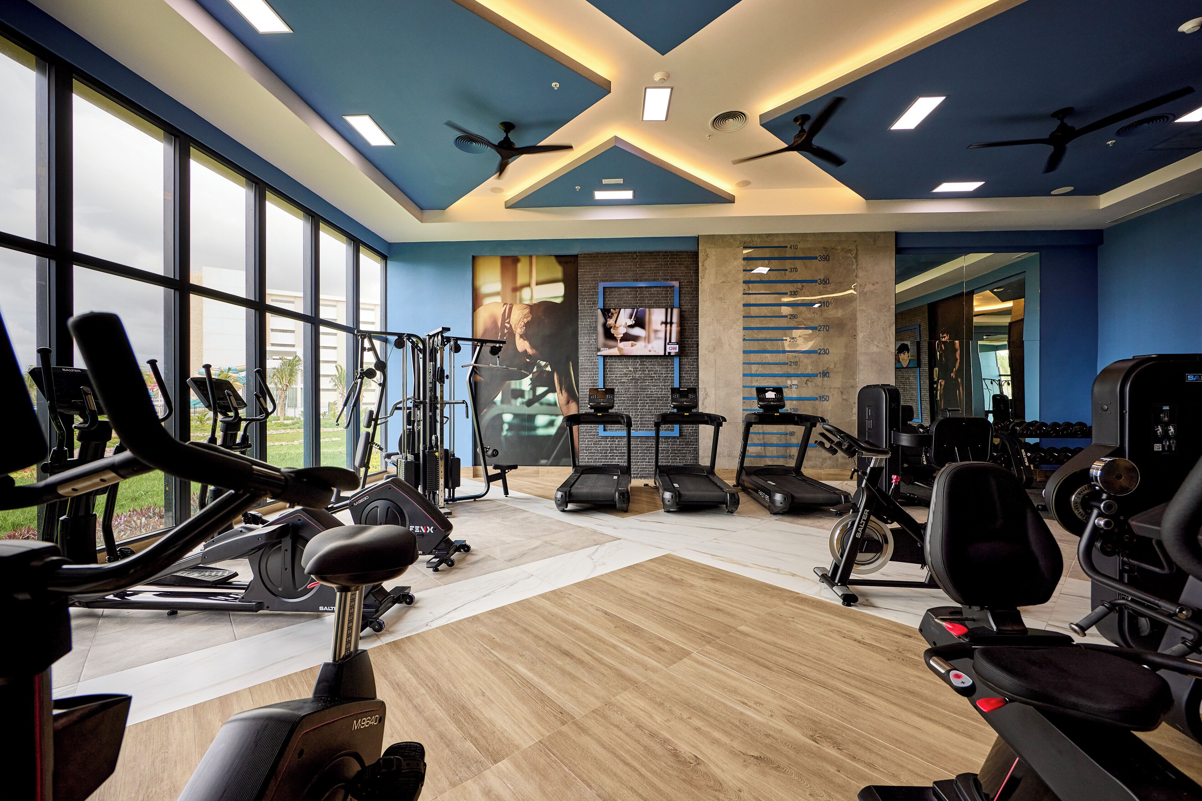 A gym with cardio machines, weight stations, and a large mirror.