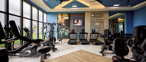 A gym with cardio machines, weight stations, and a large mirror.
