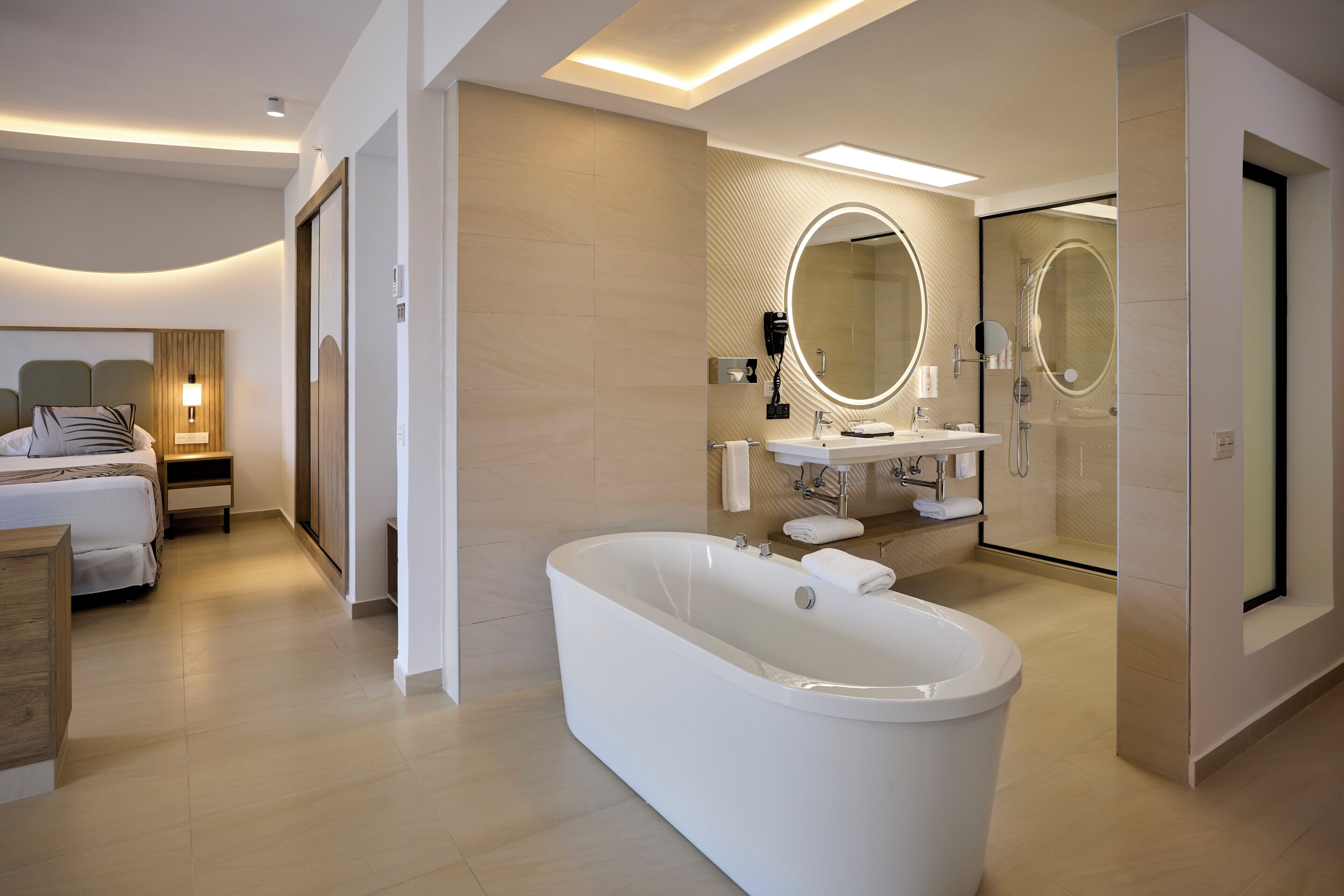 Ein modernes Hotelbad mit einer großzügigen Badewanne, einer separaten Duschkabine und einem Waschtisch mit Spiegel.