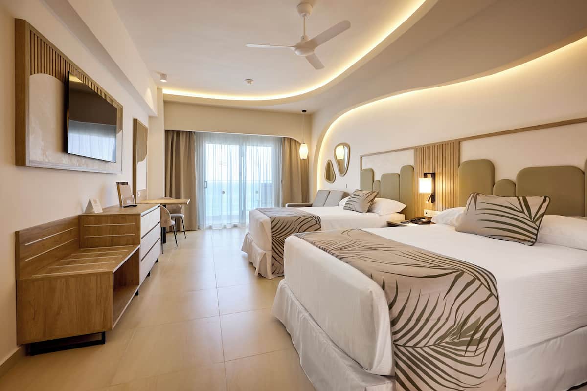 A hotel room with a bed, a desk, a chair, a TV, and a ceiling fan.