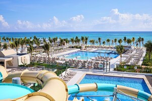 Un resort con varias piscinas, palmeras y vista al océano.