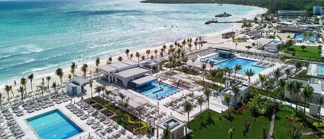 Ein Resort mit mehreren Swimmingpools, einem Strand und Blick aufs Meer.