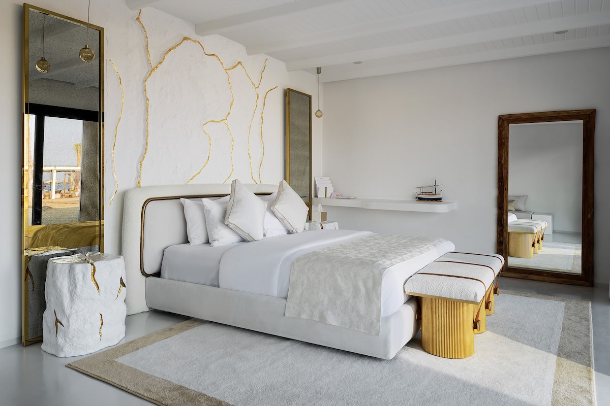 A modern bedroom with a large bed, bedside tables, and a mirror.