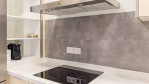 Une cuisine moderne dotée d’une cuisinière intégrée, d’une hotte en acier inoxydable et d’un dosseret carrelé gris.