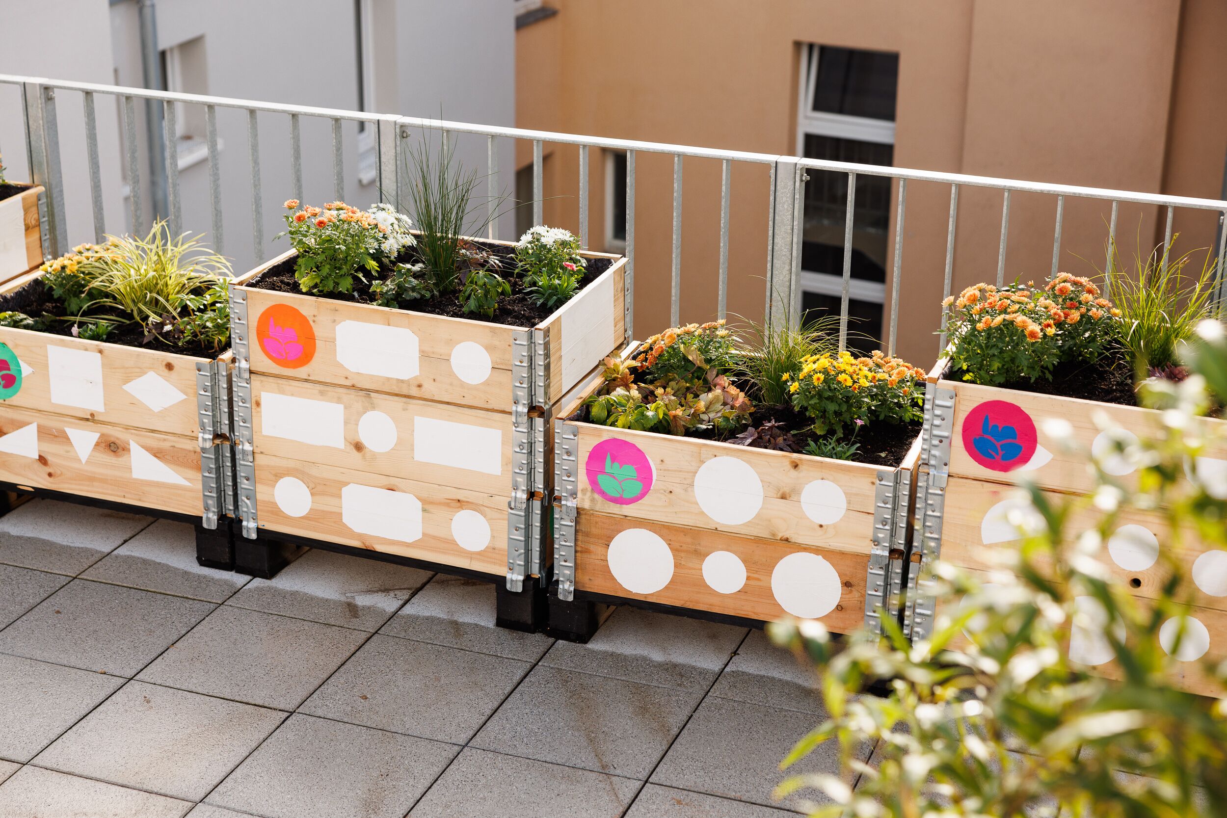 A balcony with wooden planters containing various plants and flowers.