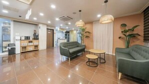 A spacious lobby with a green sofa, a small round table, and a hanging light fixture.