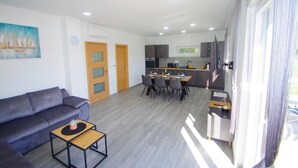 Un salon moderne comprenant un canapé, une table à manger avec des chaises, un coin cuisine avec un four à micro-ondes et une grande fenêtre avec des rideaux.