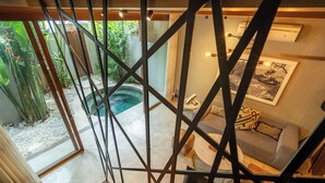 Un intérieur moderne avec un escalier, un espace de vie doté d’un canapé, et une vue sur un jardin et un jacuzzi extérieur.