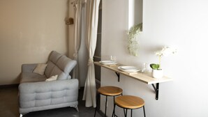 En moderne stue med en grå sofa, et lille bord med tallerkener og glas, og en potteplante.