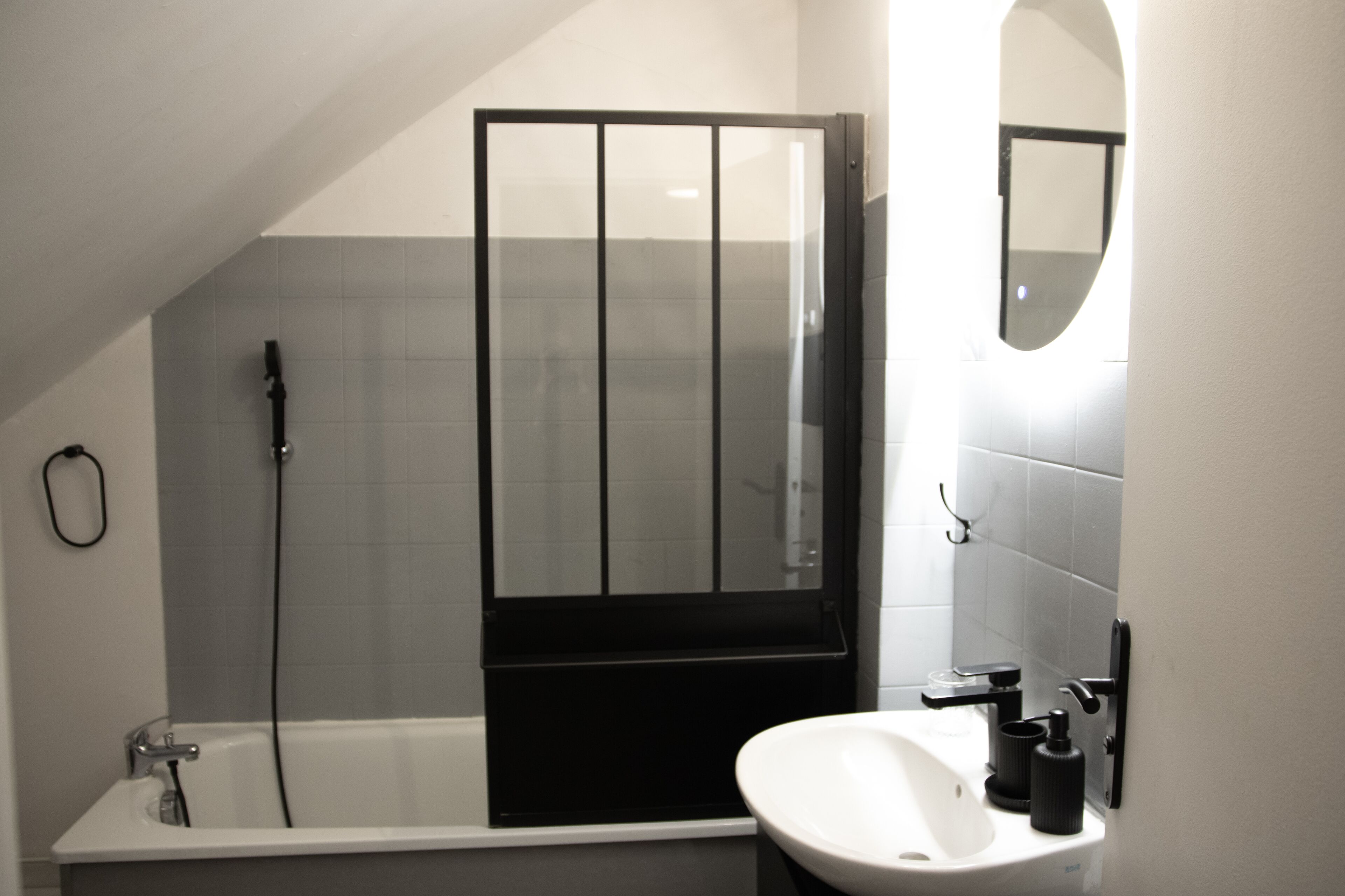 A modern bathroom with a bathtub, a glass shower enclosure, a sink, and a mirror.
