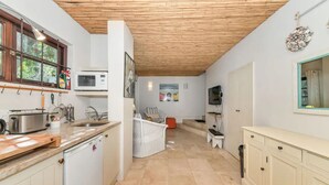 Una cocina con techo de madera, armarios blancos, un microondas y un lavabo.